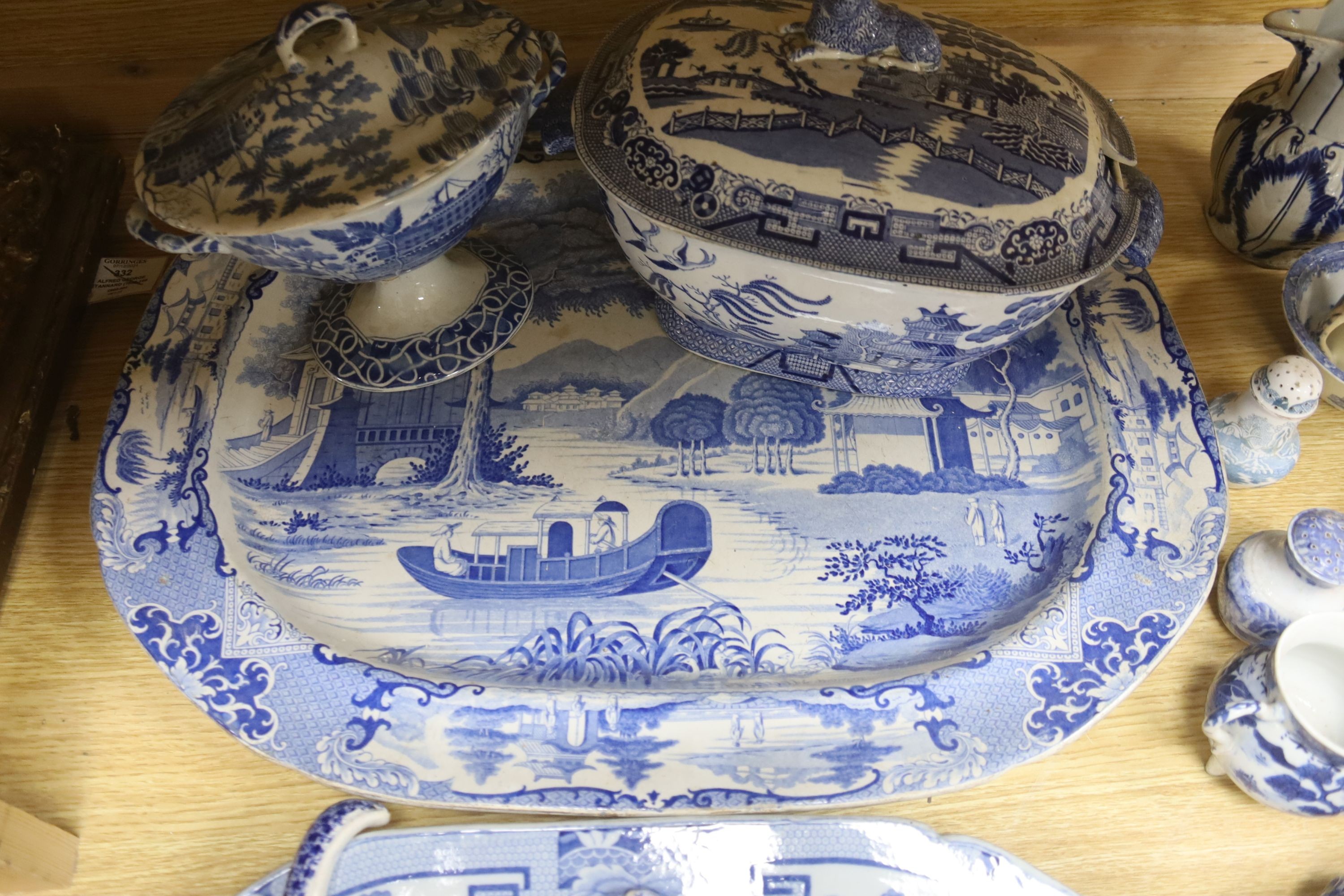 A group of 19th century blue and white pottery to include a chinoiserie pattern meat plate, 53.5 cm, a patent ironstone pheasant pattern dish, 47.5 cm, various tureens, dishes, ladles etc. a pearlware jug and two Chinese